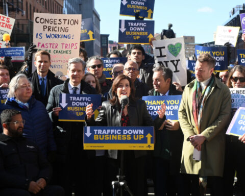 A public event with a crowd holding various signs related to congestion pricing in New York City. Photo Source: MTA.