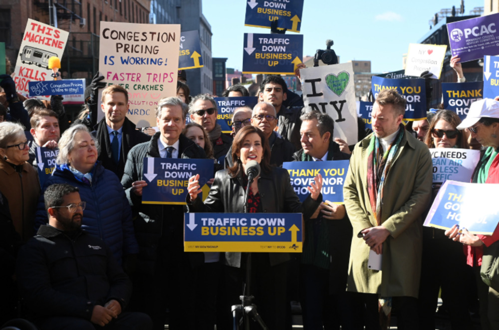 A public event with a crowd holding various signs related to congestion pricing in New York City. Photo Source: MTA.