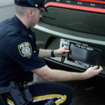 Police Officer remove the Ghost Car number Frame. Photo source: MTA