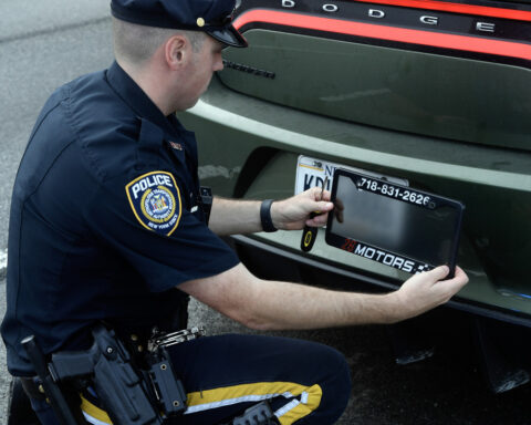 Police Officer remove the Ghost Car number Frame. Photo source: MTA