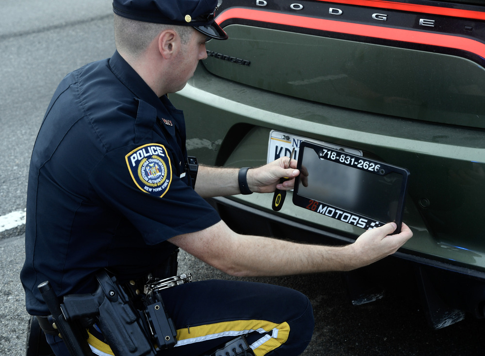 Police Officer remove the Ghost Car number Frame. Photo source: MTA