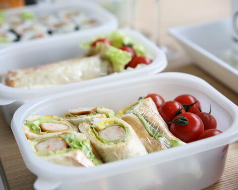 Representative Image: two white plastic containers with sandwich and tomatoes.