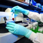 Representative Image: Scientist in a lab coat and gloves operating a piece of laboratory equipment. Photo Source: Rawpixel