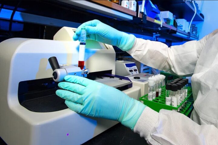 Representative Image: Scientist in a lab coat and gloves operating a piece of laboratory equipment. Photo Source: Rawpixel