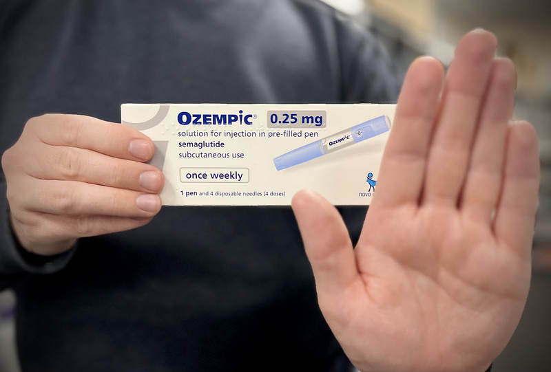 A person holding a box of Ozempic (semaglutide) 0.25 mg, which is a medication for subcutaneous use in a pre-filled pen. The packaging states that it is used once weekly and includes one pen and four disposable needles (4 doses). Photo Source: Flickr- Chemist4U (CC BY-SA 2.0)